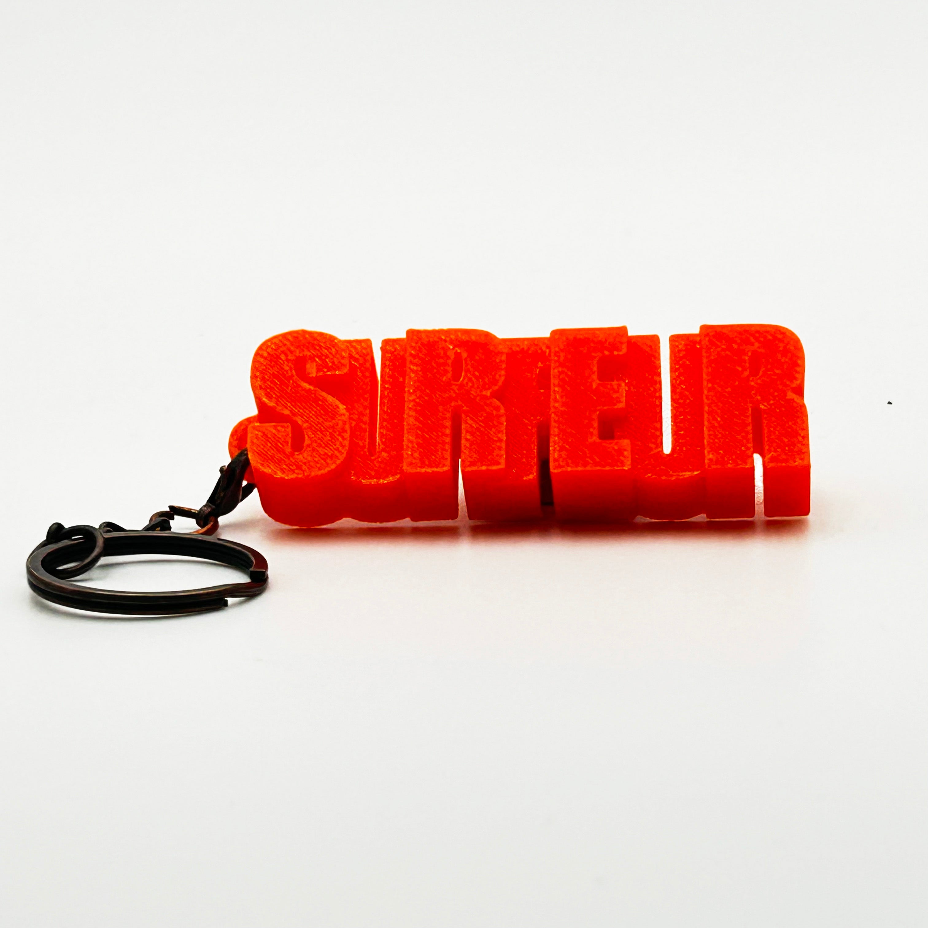 Porte-clés à message « Surfeur», imprimé en 3D, présenté dans un tube à essai.