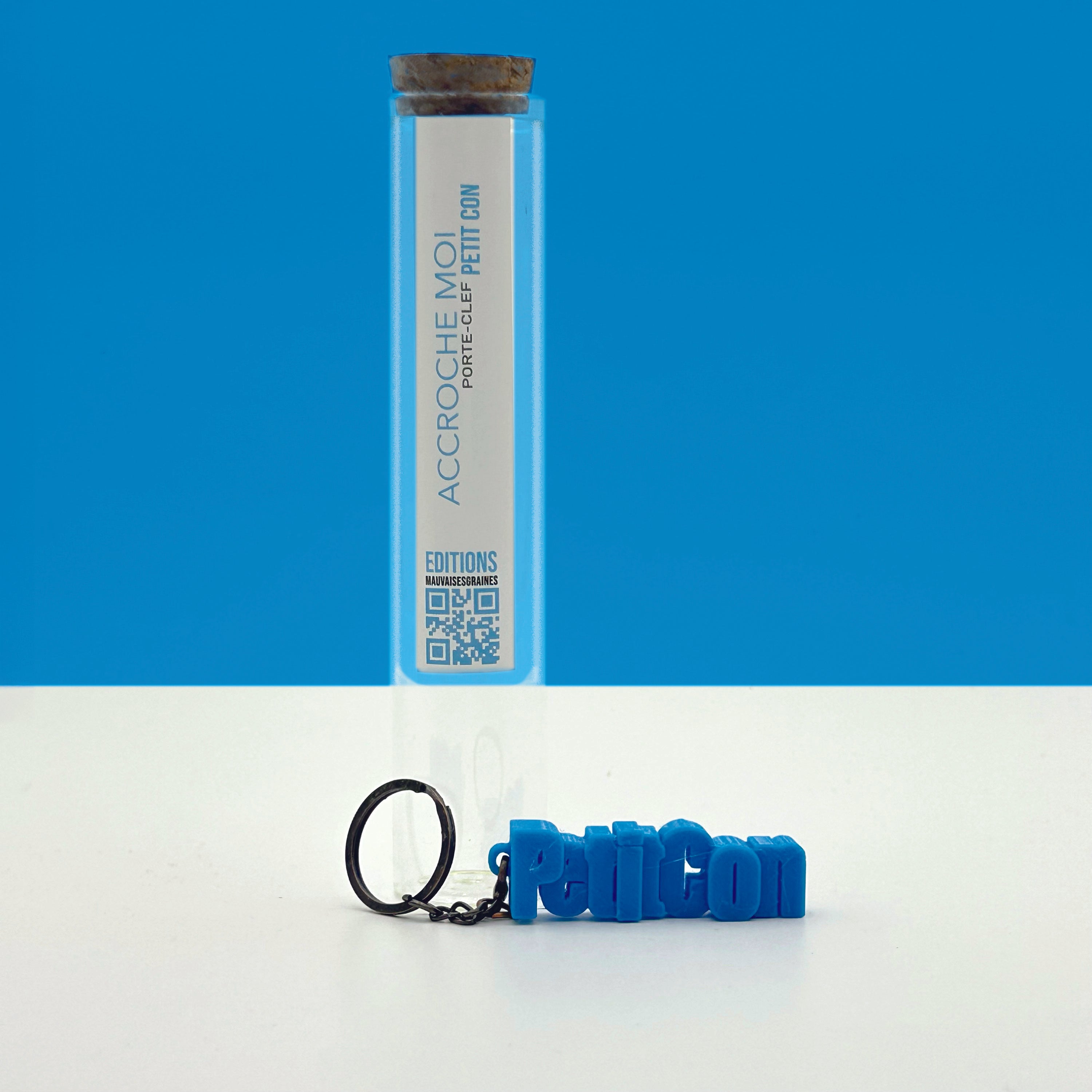 Porte-clés à message «Petit con », imprimé en 3D, présenté dans un tube à essai.