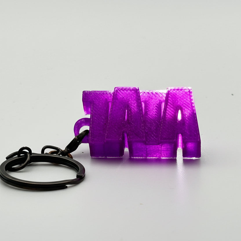 Porte-clés à message « TATA», imprimé en 3D, présenté dans un tube à essai.