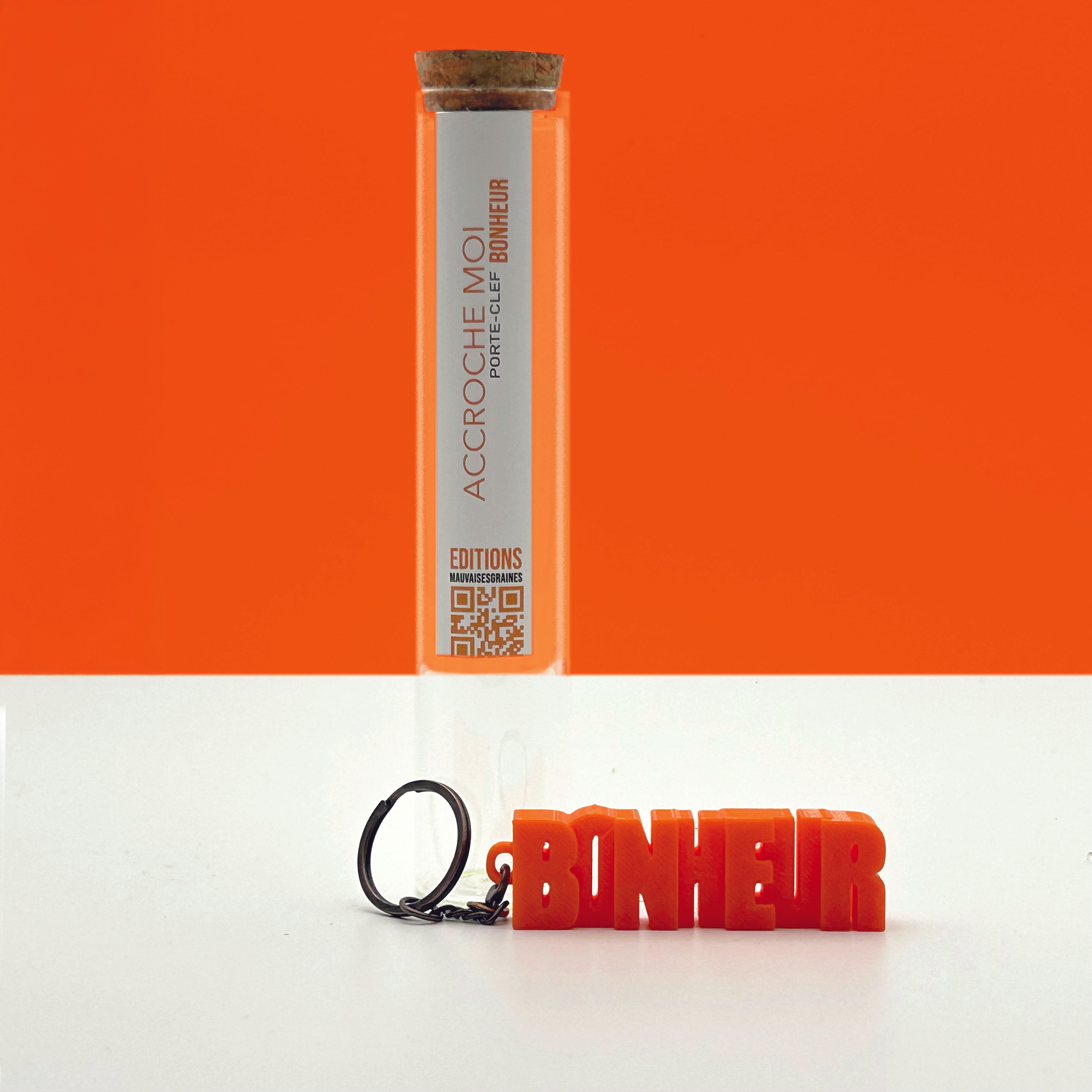 Porte-clés à message « Bonheur », imprimé en 3D, présenté dans un tube à essai.